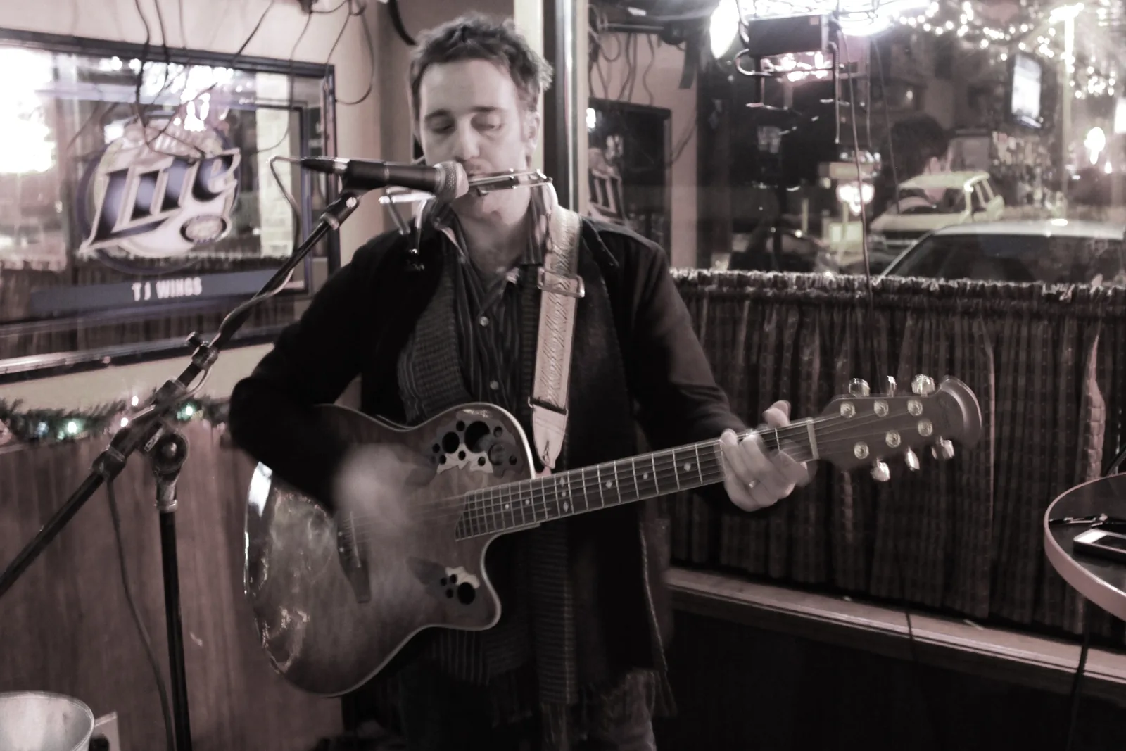 Chris Cahill singing and playing guitar at a bar show.